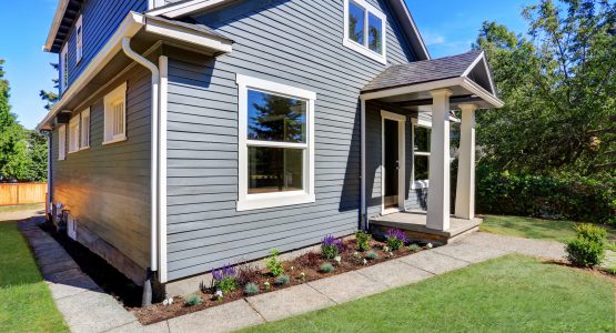 American house exterior with blue siding trim and small concrete floor porch with columns. Northwest, USA
